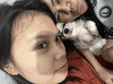 a woman holding a small white dog next to another woman wearing a sweatshirt with a circle on it