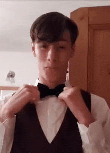 a young man is wearing a tuxedo and bow tie .