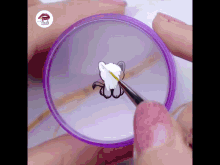 a person is painting a cat on their nails with a purple container that says nails