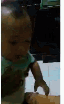 a baby in a green shirt is playing with a piece of food