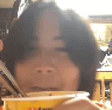 a woman is eating noodles with chopsticks from a bowl .