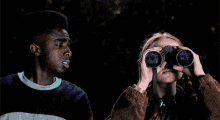a man and a woman are looking through binoculars at night