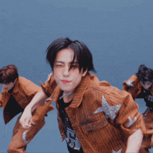 a group of young men are dancing and one of them is wearing a brown denim jacket