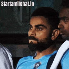 a man with a beard wearing a blue shirt is sitting in a car with other people .