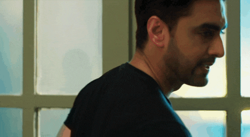 a man in a black shirt is standing in front of a window and smiling