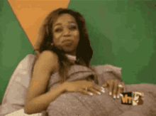 a woman is laying on a bed with a mtv logo on her lap