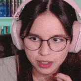a woman wearing glasses and pink headphones is looking at the camera