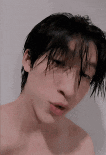 a young man with wet hair is taking a selfie .