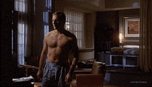 a man without a shirt is standing in a living room with the words mental troops on the bottom right