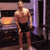 a shirtless man is standing in a gym wearing shorts and a headband