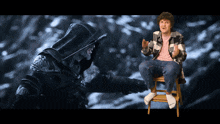 a man in a plaid shirt is sitting on a stool next to a hooded figure
