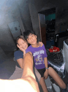 a boy wearing a purple super squad shirt sits next to a woman