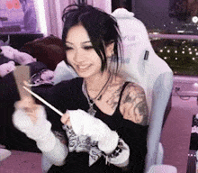 a woman with a tattoo on her arm is sitting in a chair holding a spoon and smiling .