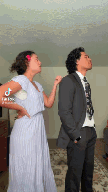 a woman in a dress is standing next to a man in a suit and tie ..
