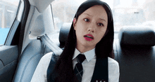 a woman in a school uniform is sitting in the back seat of a car .