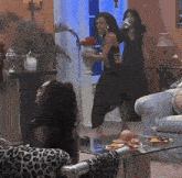 a woman in a black dress stands in a living room