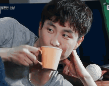 a man drinking from an orange cup with the number 3 on the bottom right