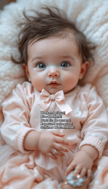 a baby wearing a pink dress with a bow on it is laying on a pillow