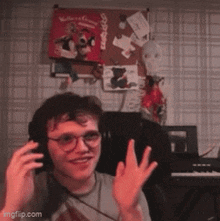a young man wearing headphones is waving his hands in front of a bulletin board with a picture of a penguin on it