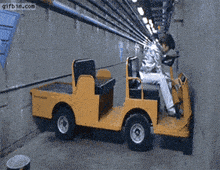 a person is driving a yellow vehicle in a tunnel with gifbin.com written on the bottom right