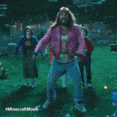 a group of people standing in a field with a minecraft movie advertisement in the background