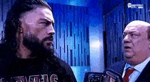 a man with a beard is standing next to a man in a suit and tie .