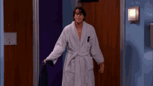 a man in a bathrobe is standing in front of a door with a light on it