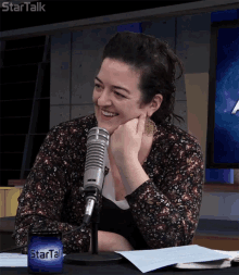 a woman is smiling in front of a microphone with a startalk can in front of her
