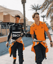 a man wearing an orange shirt that says dell technology walks next to another man
