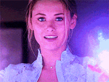 a close up of a woman 's face with a purple light in the background