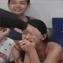 a group of women are sitting on a couch and one of them is laughing .