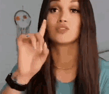 a woman with long hair is making a funny face and pointing at something with her finger .