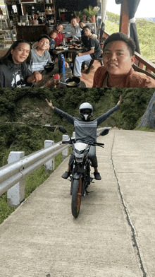 a man riding a motorcycle with his arms outstretched next to a group of people sitting at a table