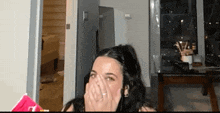 a woman is covering her mouth with her hand in a living room .