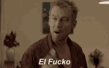 a man in a robe is holding up a cell phone and says el fucko on the bottom