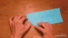 a person is holding a piece of blue paper with the words made in animotica above them