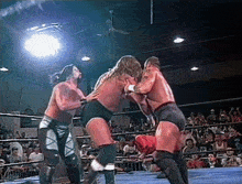 a group of wrestlers are fighting in a ring with a crowd watching
