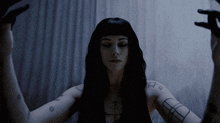 a woman with black hair has a tattoo on her arm that says ' a '