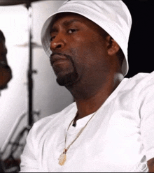 a man wearing a white hat and a gold necklace looks to the side