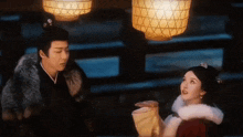 a man and a woman are standing next to each other under lanterns in a dark room .