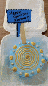 a birthday cake in a styrofoam container with a sign that says happy birthday kanchan ji