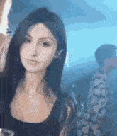 a woman is standing in a dark room looking at the camera while holding a glass of wine .