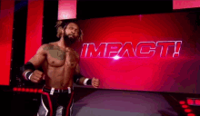 a wrestler is standing in front of a large screen that says impact .