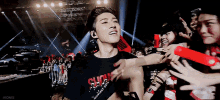 a man wearing a black shirt that says ' seoul ' on it is surrounded by fans