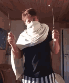 a man with a scarf around his face is holding a pair of scissors in front of his face