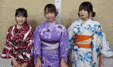 three asian women wearing kimonos are standing next to each other