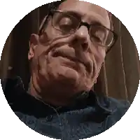 a man wearing glasses and a blue shirt looks up at the camera