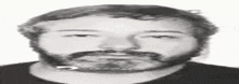 a black and white photo of a man with a beard and a black shirt .