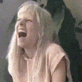 a woman with long blonde hair is laughing with her mouth wide open