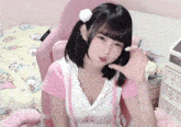 a girl wearing a pink and white shirt with a white pom pom on her hair